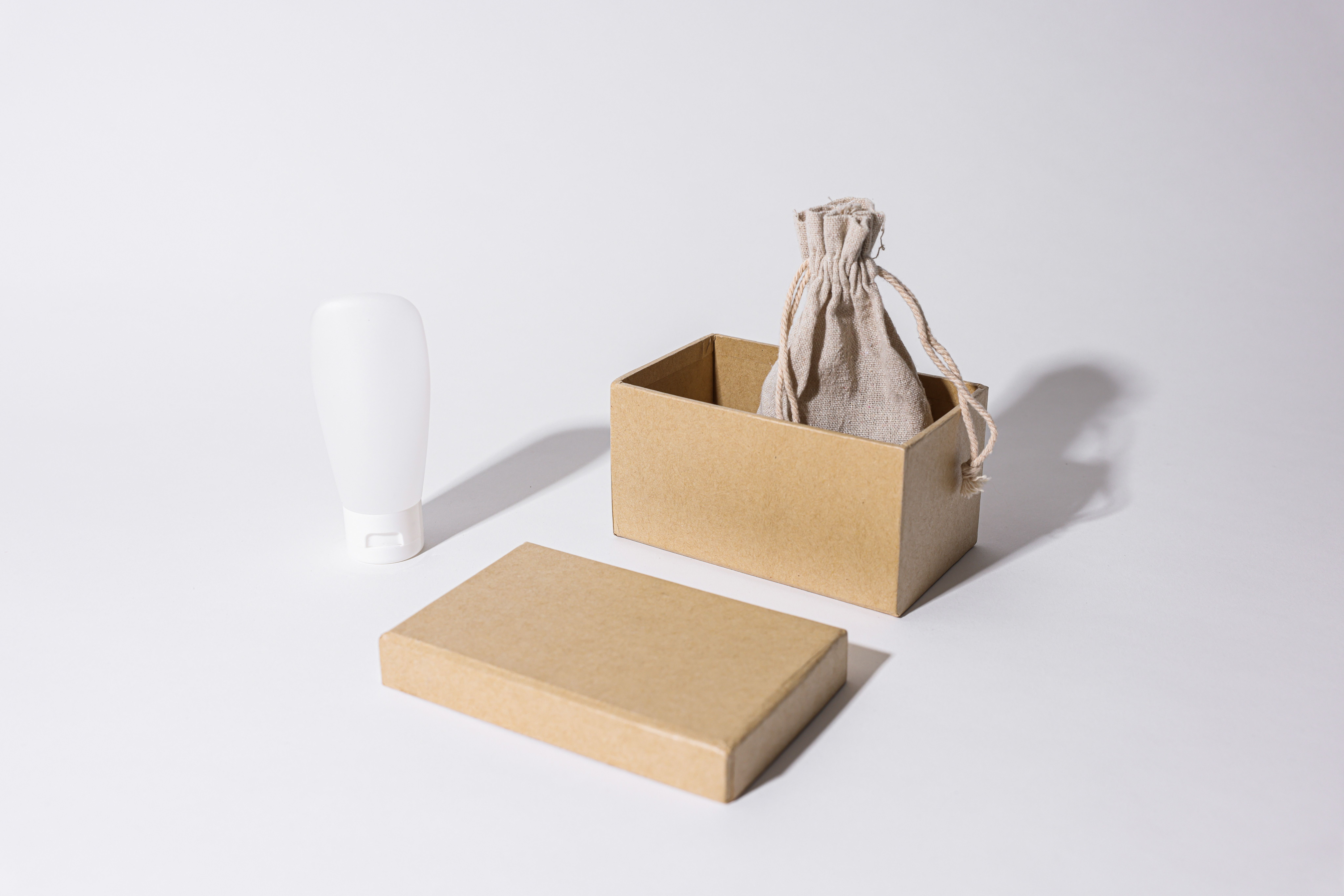 Stylish minimalist product mockup with a custom cardboard box, linen pouch and cream tube