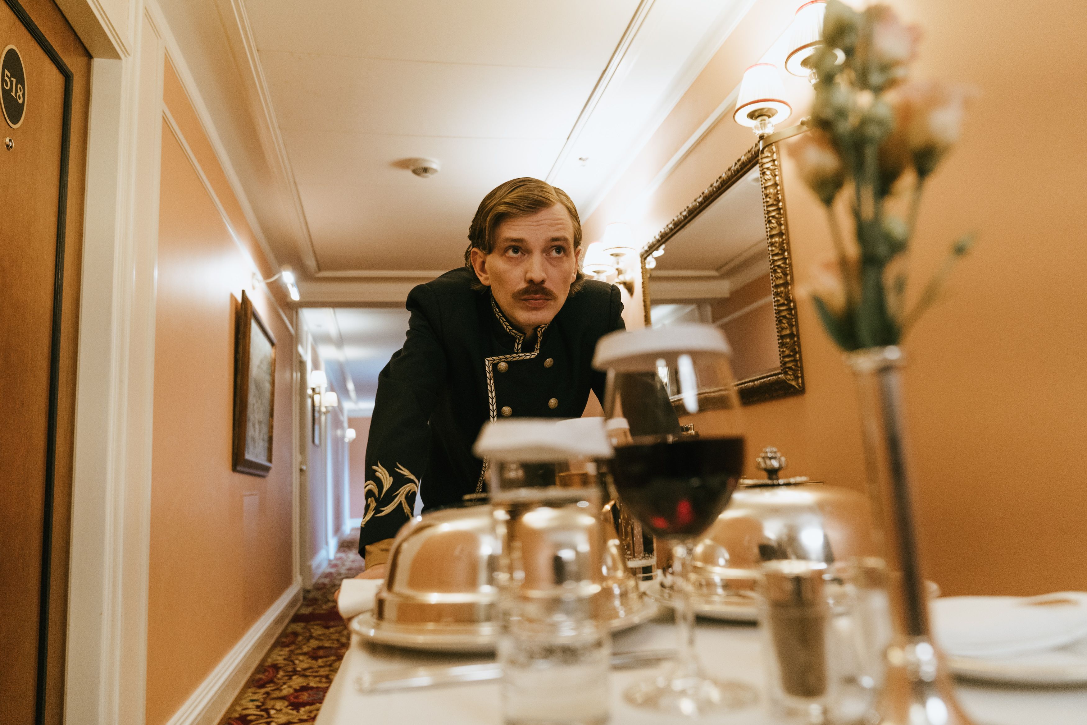 Hotel staff member in uniform delivering room service in an elegant hallway, example of five-star hospitality