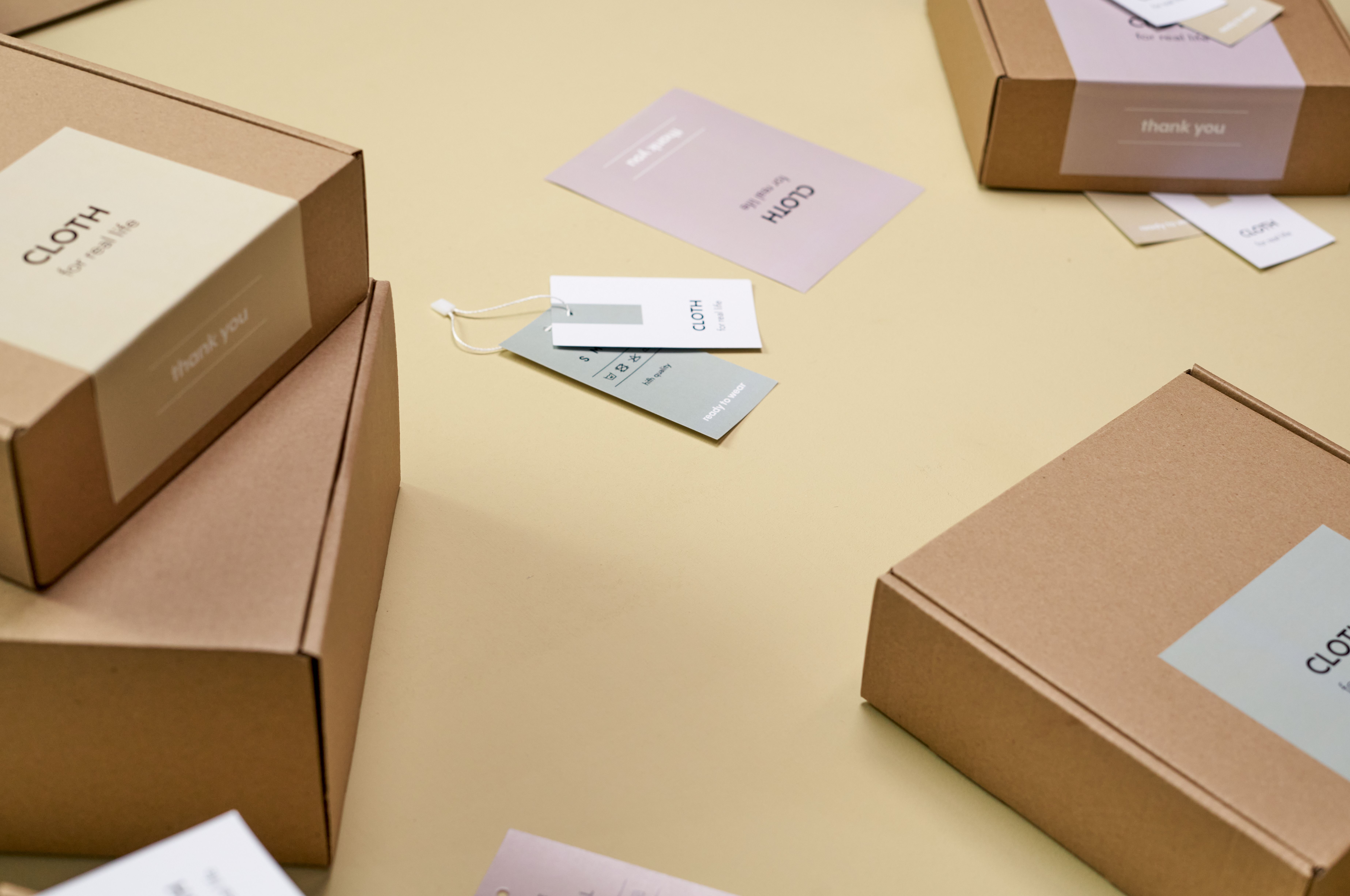 Minimalist custom cardboard packaging boxes with labels arranged on a yellow surface